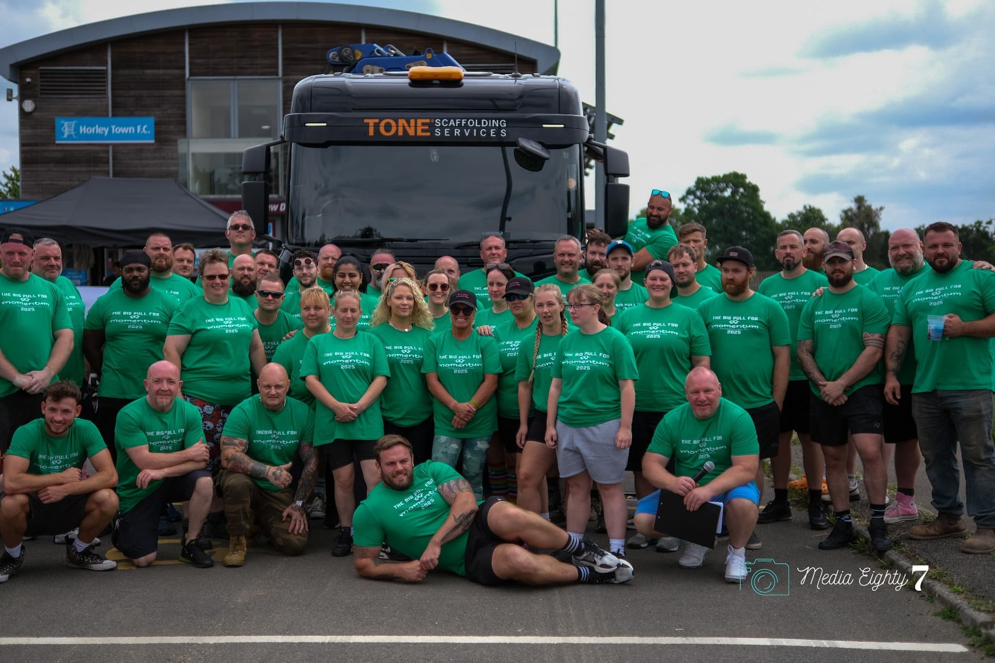 Group photo in green Momentum Children's Charity shirts in front of a TONE Scaffolding truck